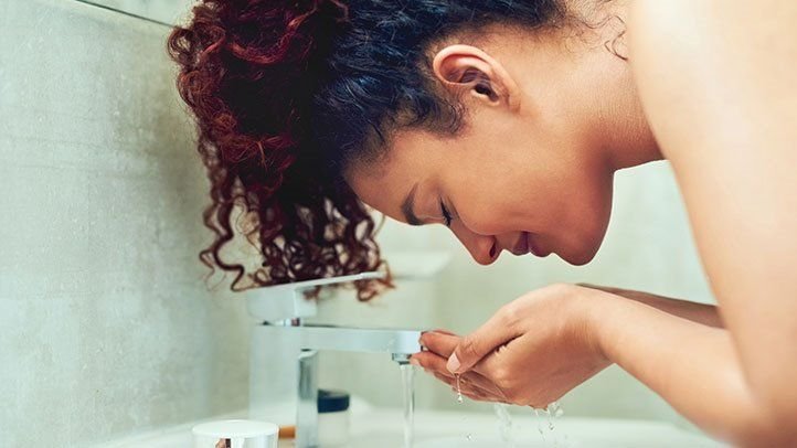 A woman using a facial cleanser after a workout to maintain clear skin.